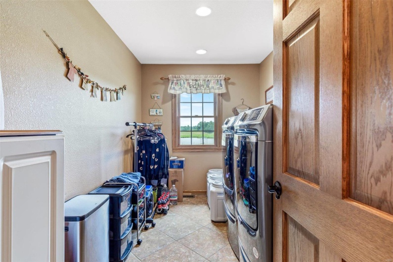 Washroom with washing machine and clothes dryer and light tile patterned floors