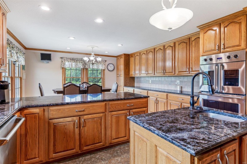 Kitchen with backsplash, ornamental molding, hanging light fixtures, and a notable chandelier