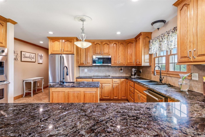 Kitchen featuring decorative backsplash, ornamental molding, stainless steel appliances, sink, and decorative light fixtures