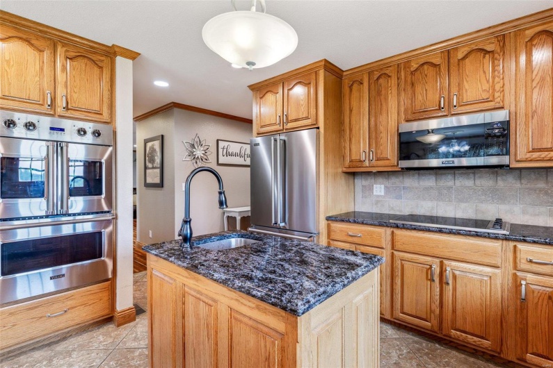 Kitchen featuring a center island with sink, hanging light fixtures, sink, ornamental molding, and appliances with stainless steel finishes