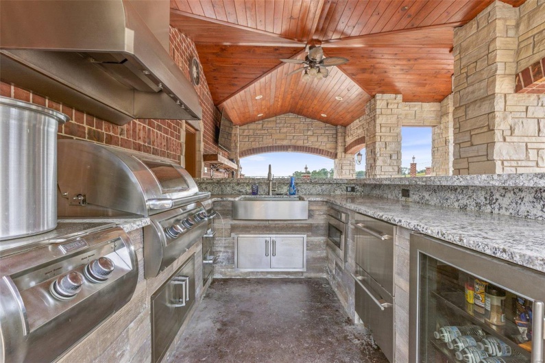 View of patio / terrace featuring an outdoor kitchen, ceiling fan, sink, grilling area, and wine cooler
