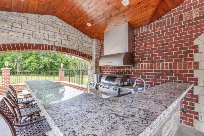 View of patio with exterior bar, an outdoor kitchen, and a grill