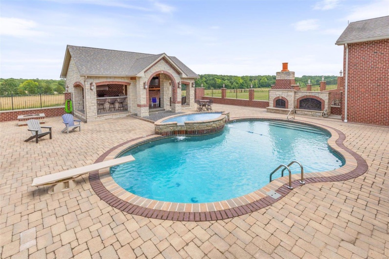 View of swimming pool featuring pool water feature, a patio area, an in ground hot tub, and exterior fireplace