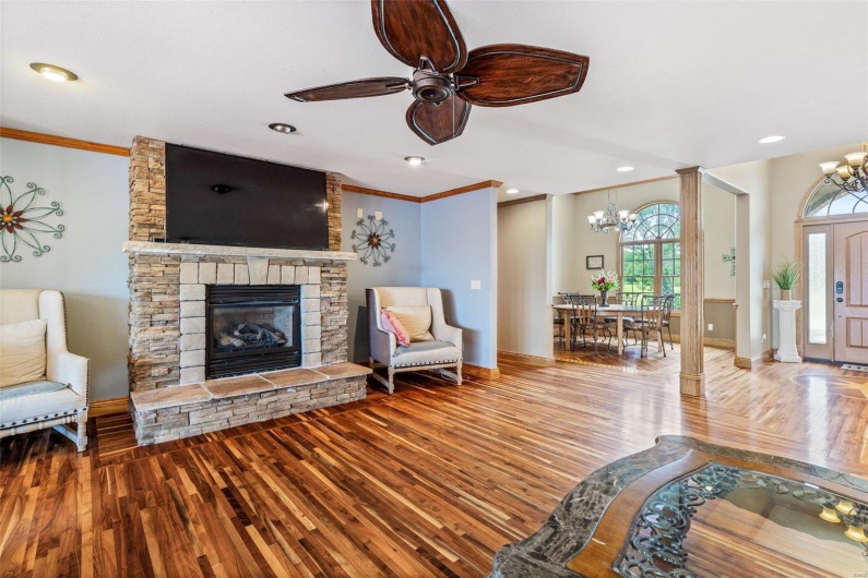Living room with hardwood / wood-style floors, ceiling fan with notable chandelier, and ornamental molding