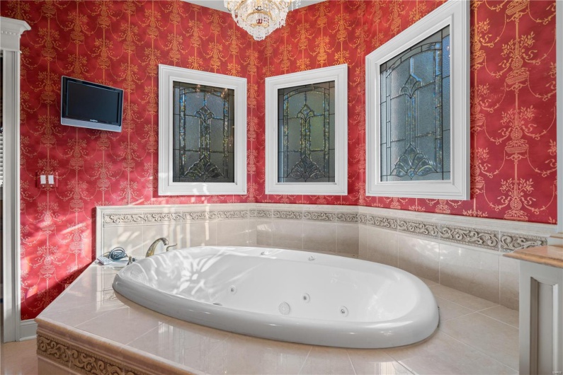 Bathroom featuring a relaxing tiled tub and a notable chandelier