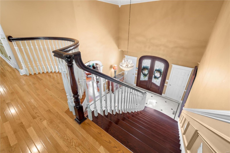 Stairway featuring a high ceiling, an inviting chandelier, french doors, crown molding, and wood-type flooring