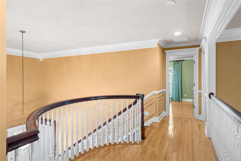 Hall with light hardwood / wood-style floors and crown molding