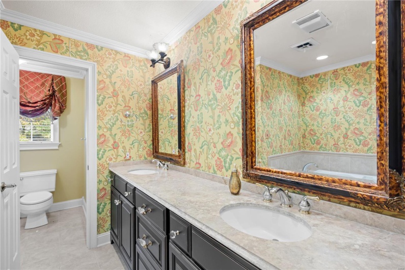 Bathroom with vanity, toilet, ornamental molding, and a tub to relax in