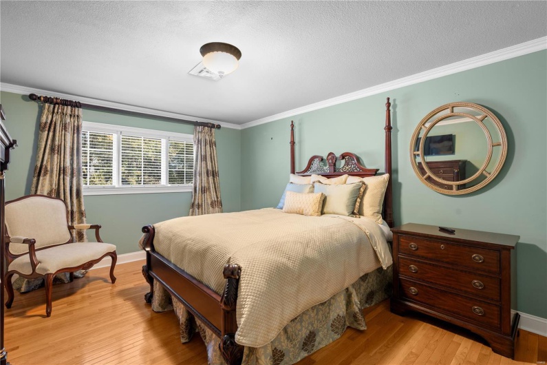 Bedroom with light hardwood / wood-style flooring, a textured ceiling, and ornamental molding