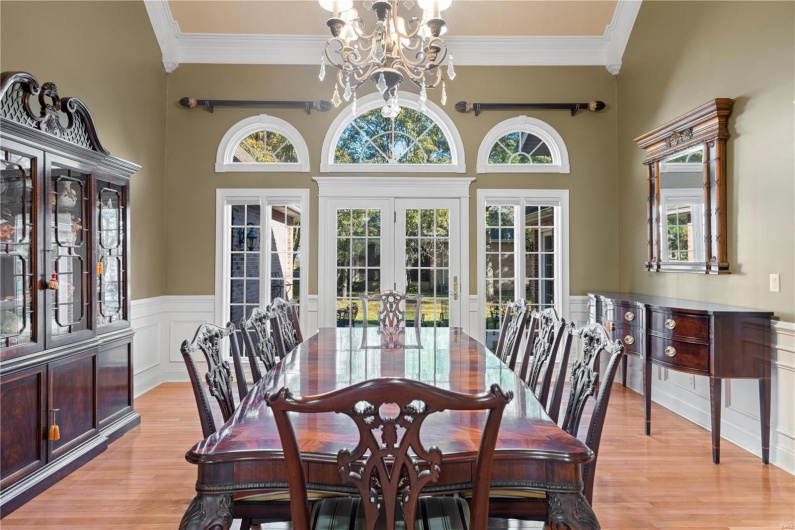 Dining area with french doors, a towering ceiling, light hardwood / wood-style floors, and a notable chandelier