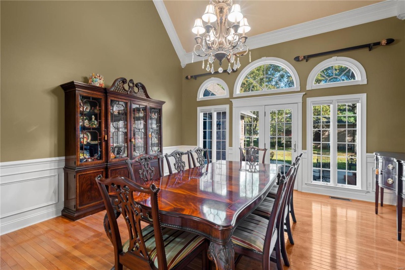 Dining space featuring french doors, an inviting chandelier, high vaulted ceiling, light hardwood / wood-style floors, and ornamental molding