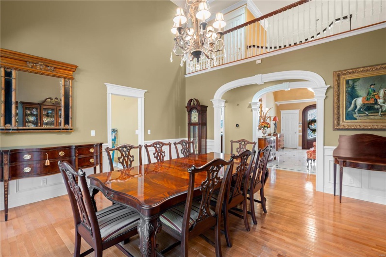 Dining space featuring ornate columns, light hardwood / wood-style flooring, a towering ceiling, and a chandelier
