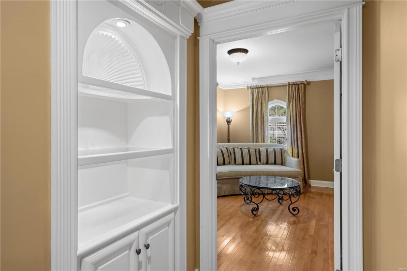 Hall with wood-type flooring and crown molding
