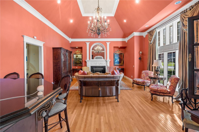 Home office featuring ornate columns, light hardwood / wood-style flooring, high vaulted ceiling, a notable chandelier, and ornamental molding