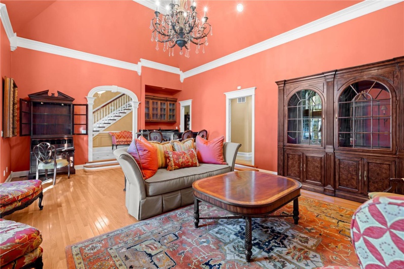 Living room featuring light wood-type flooring, crown molding, high vaulted ceiling, and an inviting chandelier