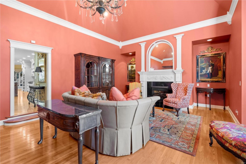 Living room featuring wood-type flooring, ornamental molding, a high ceiling, and an inviting chandelier