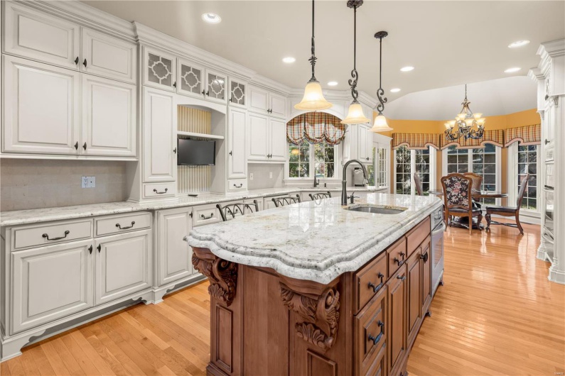 Kitchen with a notable chandelier, a kitchen island with sink, white cabinets, sink, and decorative light fixtures