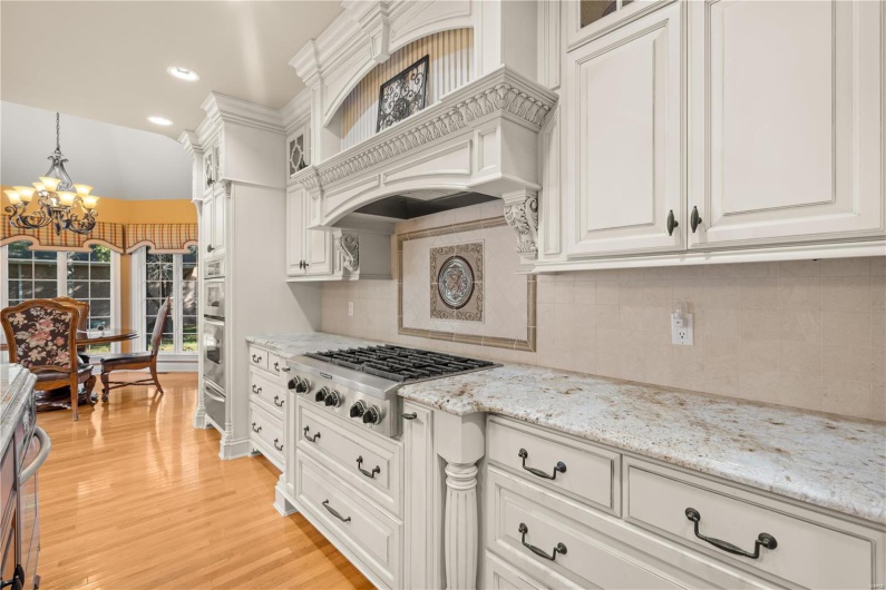 Kitchen featuring tasteful backsplash, stainless steel gas cooktop, an inviting chandelier, light hardwood / wood-style flooring, and hanging light fixtures