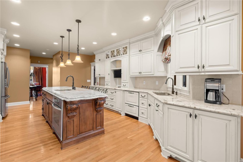 Kitchen with white cabinets, light wood-type flooring, a kitchen island with sink, and sink