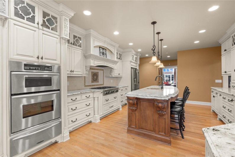 Kitchen with light stone countertops, stainless steel appliances, white cabinetry, and light hardwood / wood-style flooring
