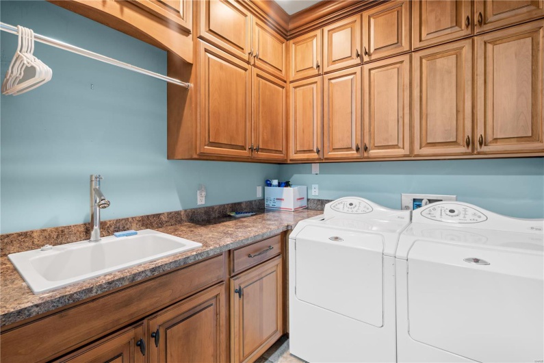 Clothes washing area with washer and dryer, sink, and cabinets