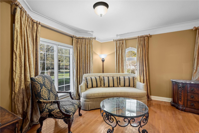 Sitting room featuring wood-type flooring, a wealth of natural light, and ornamental molding