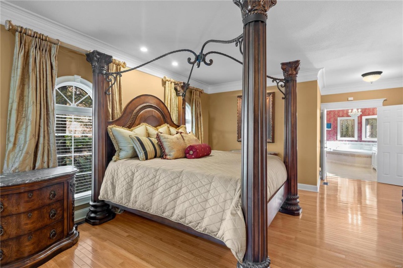 Bedroom with ensuite bathroom, light hardwood / wood-style flooring, and crown molding