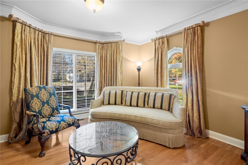 Living area with hardwood / wood-style floors, a healthy amount of sunlight, and ornamental molding