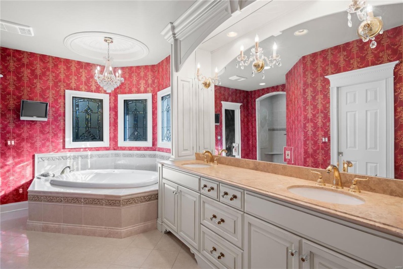 Bathroom with tiled tub, tile patterned flooring, vanity, and an inviting chandelier