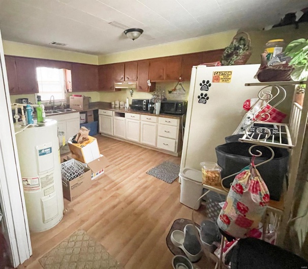 Kitchen with water heater, sink, white cabinets, and light hardwood / wood-style floors