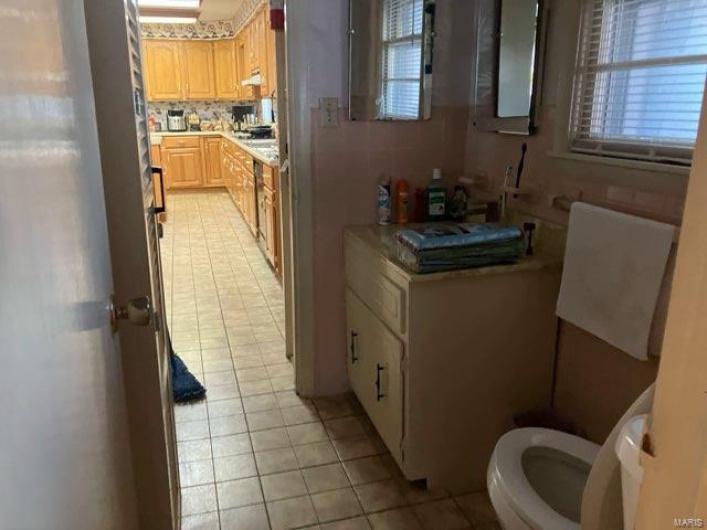 Kitchen with light tile patterned floors, light brown cabinetry, and tasteful backsplash