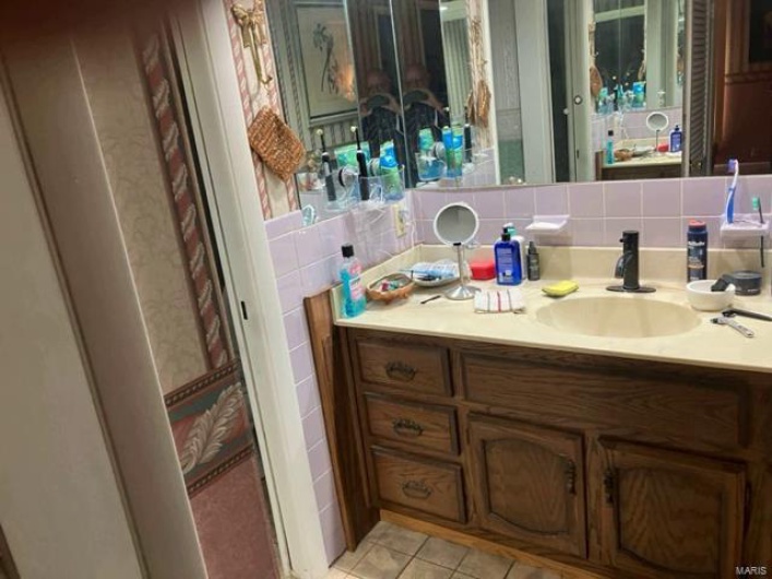Bathroom with tile patterned flooring, vanity, and backsplash