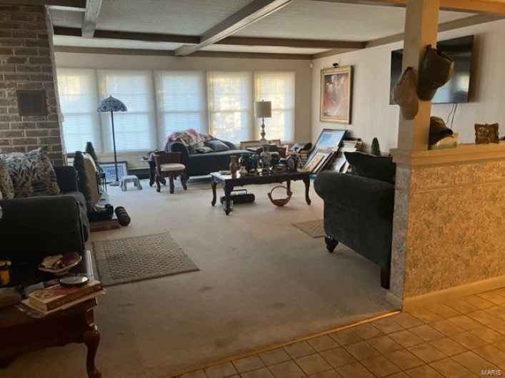 Carpeted living room featuring beam ceiling