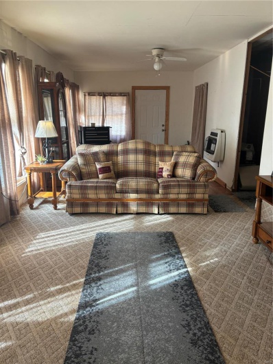 Carpeted living room with ceiling fan and heating unit