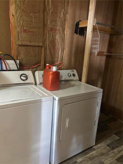 Laundry area featuring independent washer and dryer, dark hardwood / wood-style floors, and wood walls