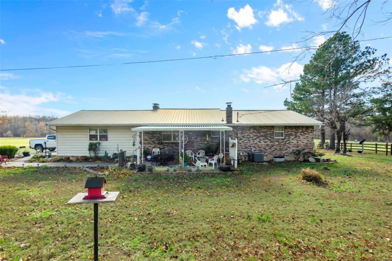Rear view of house featuring central AC, a patio area, and a lawn