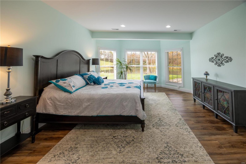 Bedroom in lower level with LVP flooring and view of lake in backyard.