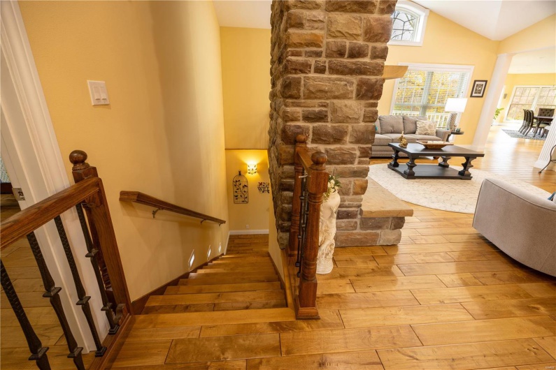Staircase to lower level with wooden flooring and vaulted ceiling.
