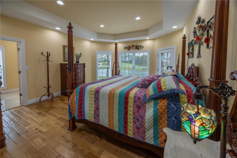 Bedroom with hardwood flooring and view of backyard.