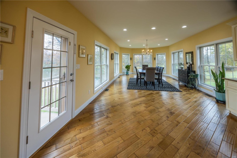 Dining area with crystal chandelier, light hardwood flooring, and view of lake in backyard.