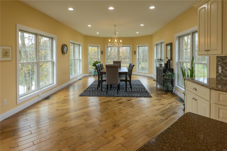 Dining area featuring plenty of natural light, light hardwood flooring, and crystal chandelier with view of lake in backyard.