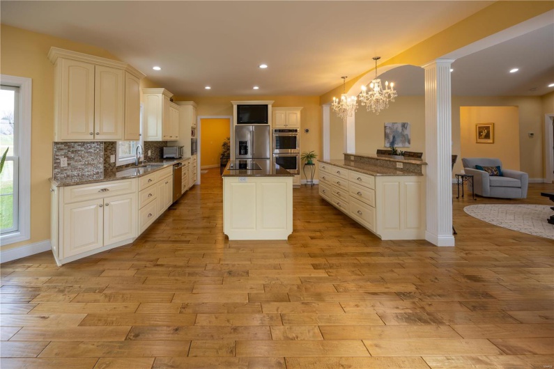 Kitchen featuring sink, hanging light fixtures over breakfast bar, light wood flooring, and appliances with stainless steel finishes.