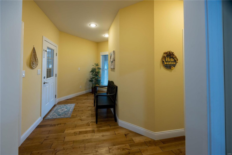 Entry to home from garage with natural light and light hardwood flooring.