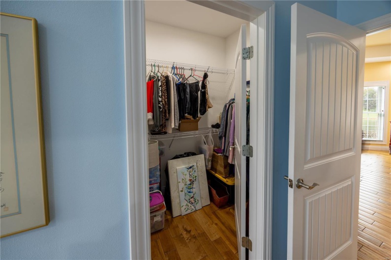 Walk-in closet in primary bathroom with light hardwood flooring.