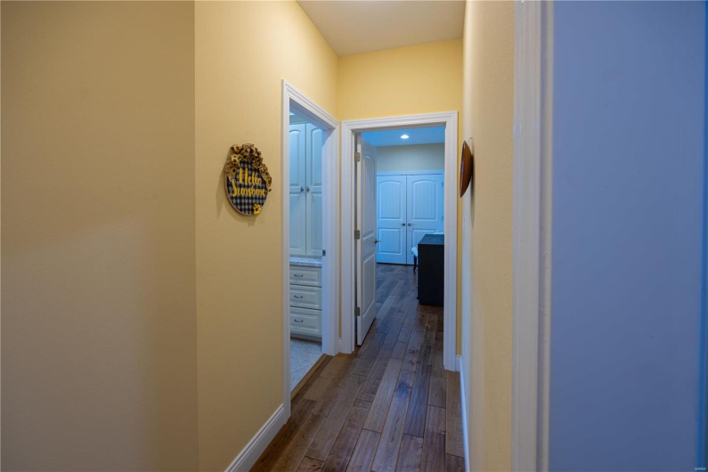 Hallway off kitchen looking towards bedroom and bathroom with hardwood flooring.