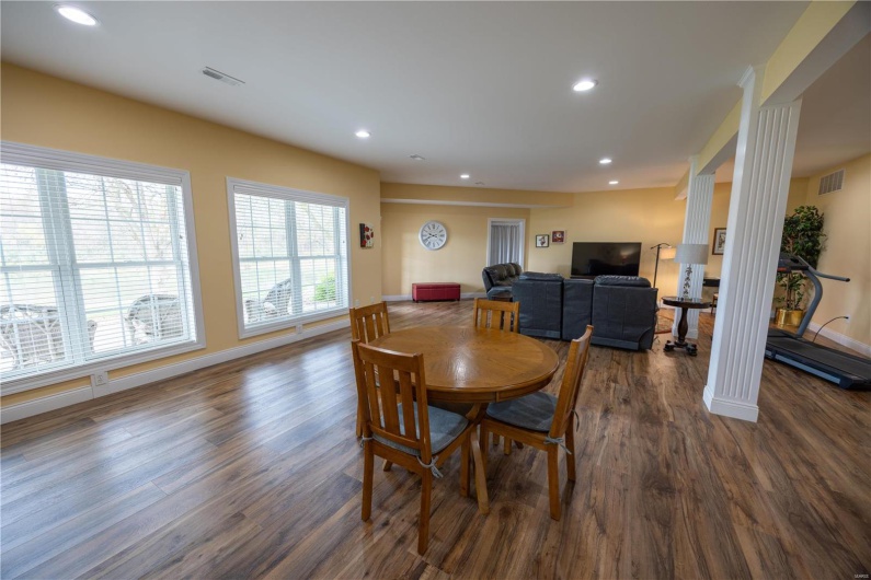 Family room featuring ornate columns and LVP flooring with view of lake in backyard.