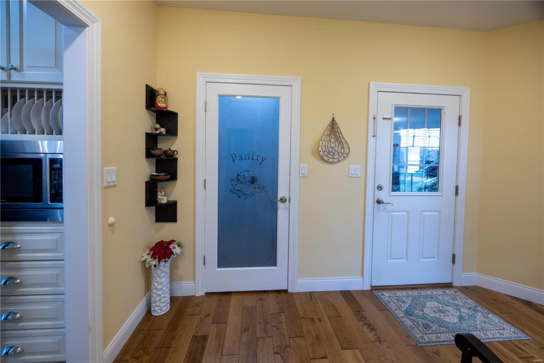 Entry from garage featuring pantry and hardwood flooring.