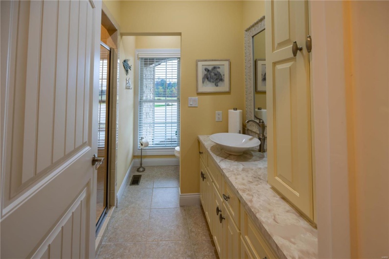 Bathroom featuring marble patterned flooring, vanity, toilet, and an enclosed shower.