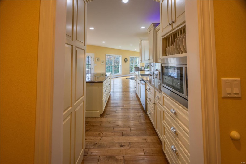 Kitchen with sink, stainless steel appliances, kitchen island, cream cabinets, and light hardwood flooring.