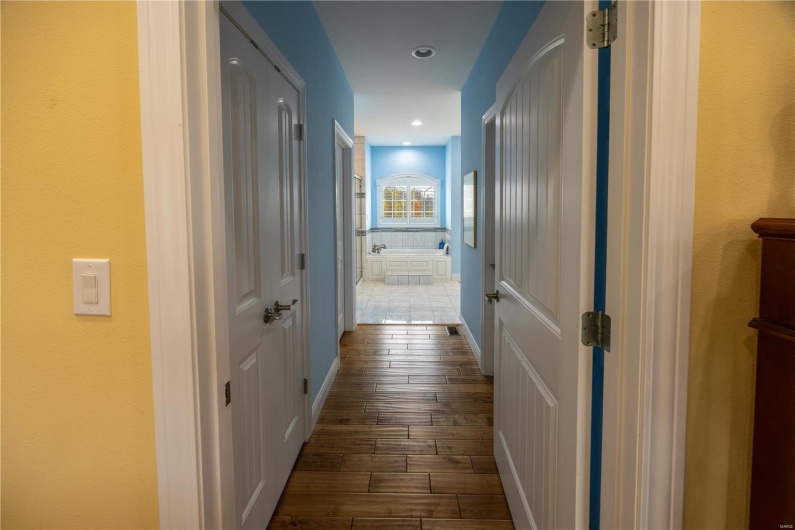 Hall to primary bathroom with hardwood flooring.
